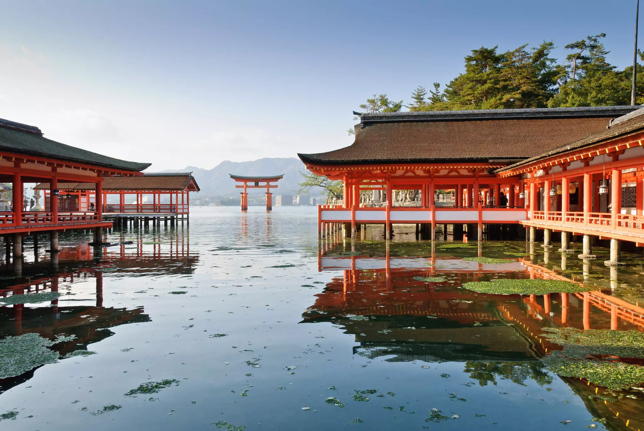 A structure with red columns over a lake; a red gate is in the water in the background.