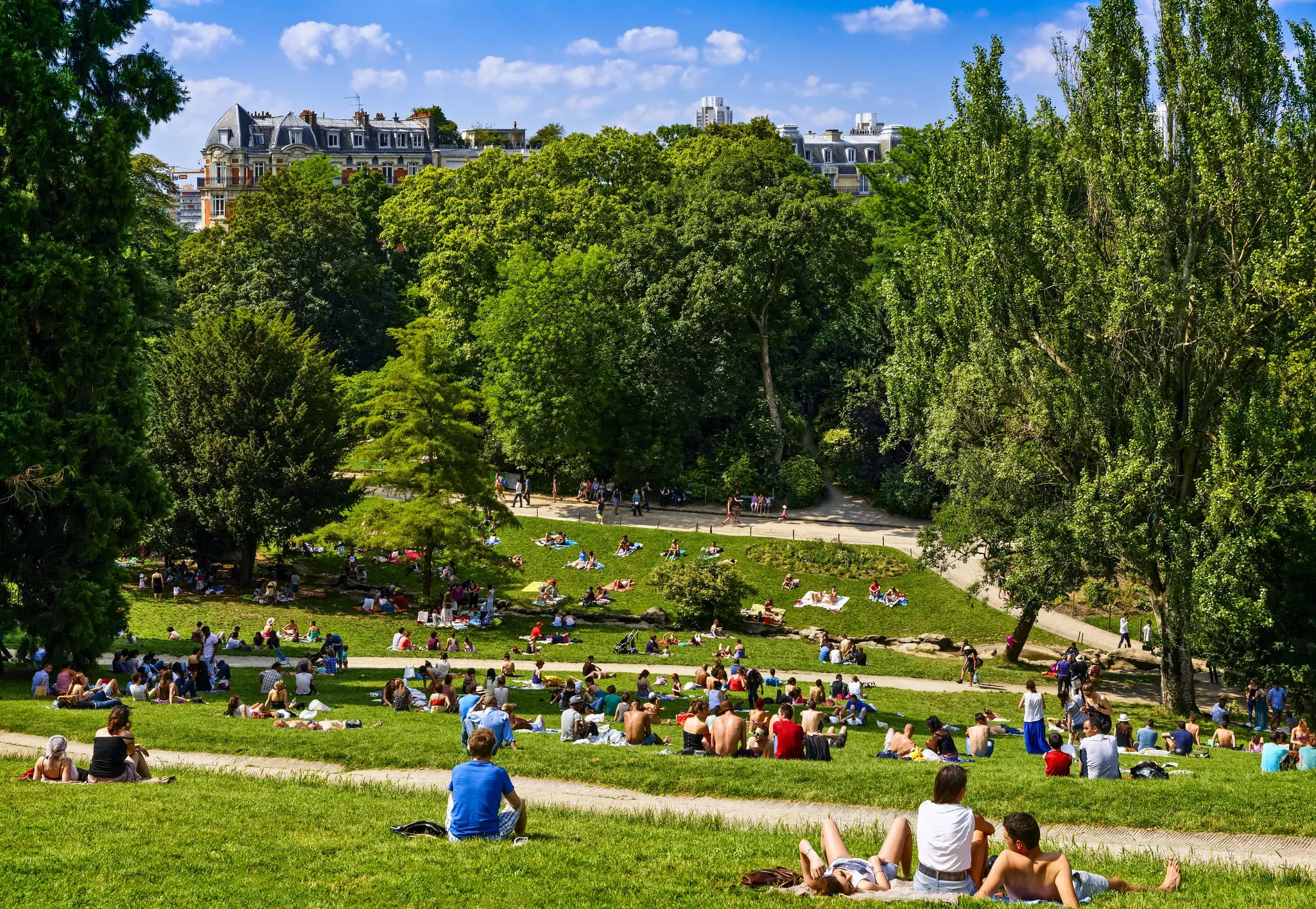 People sit on lush green grass in a Paris park.
