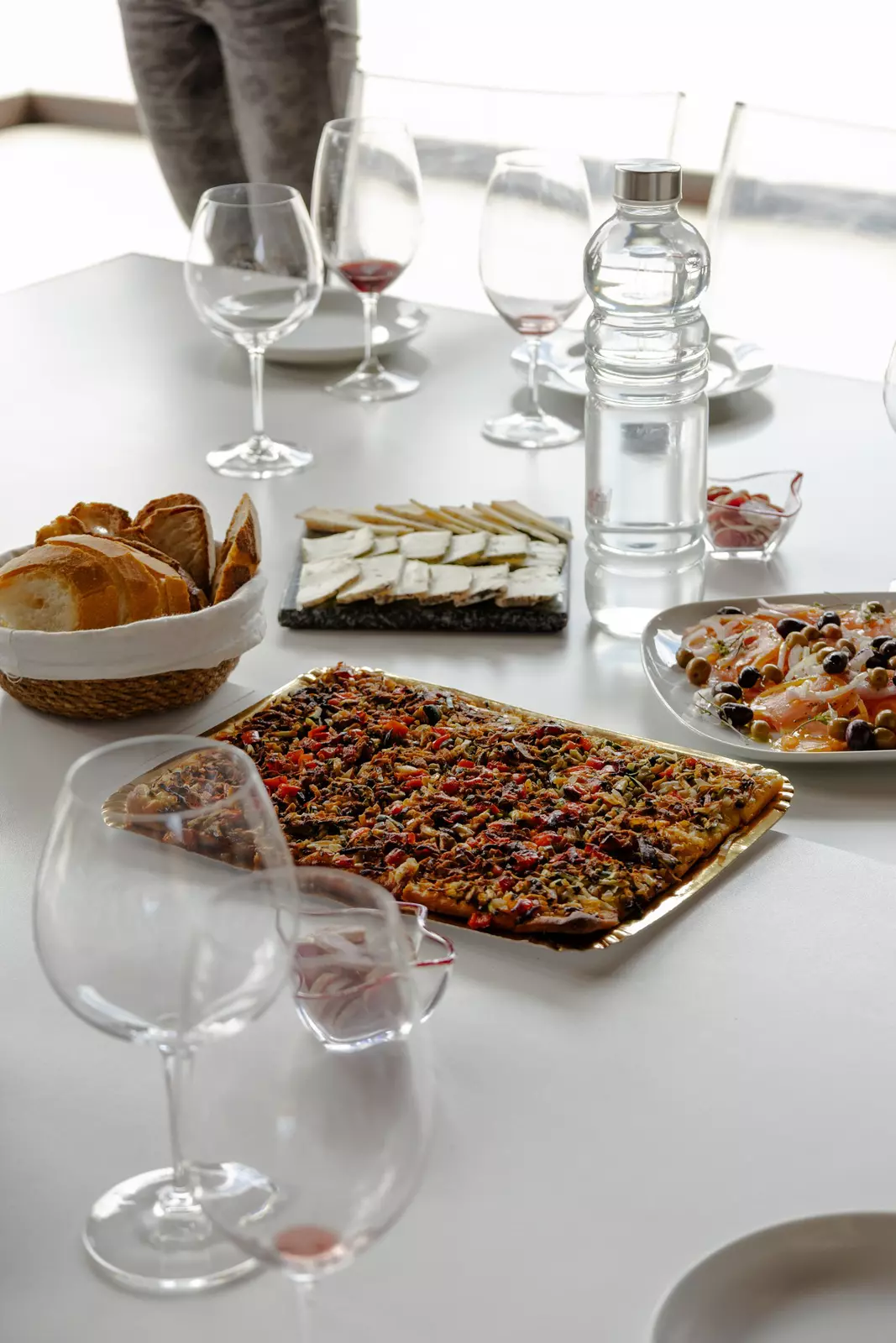 Serving dishes of food on a white tablecloth.