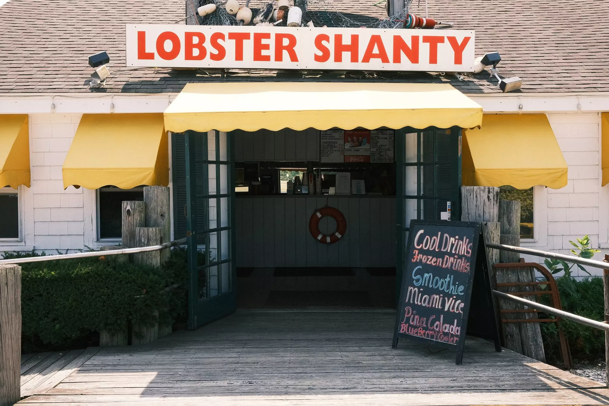 Entrance to a restaurant called "Lobster Shanty" with a blackboard advertising cool drinks, frozen drinks and smoothies.