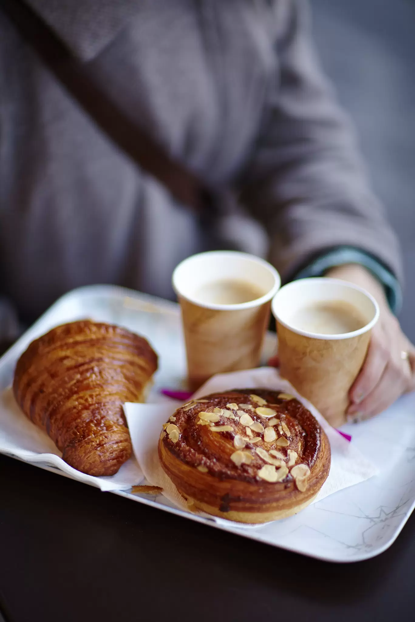 Hand carrying a breakfast of croissant, coffee and escargot..