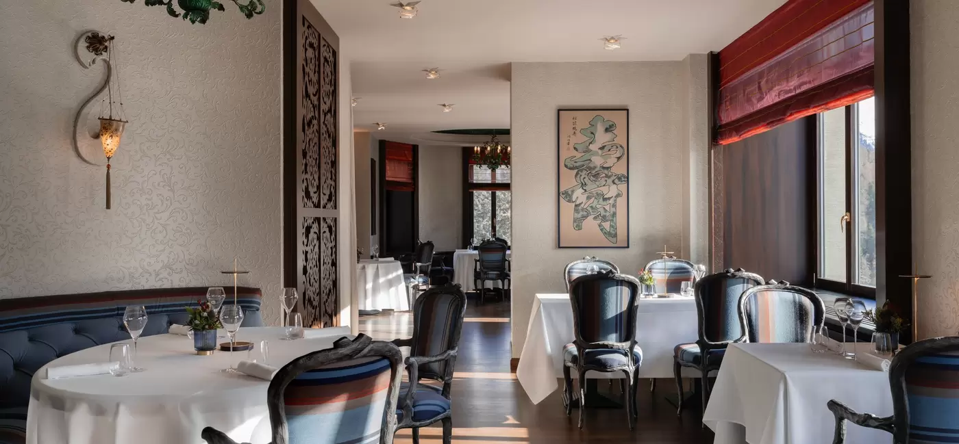 An empty restaurant with tables with white tablecloths.