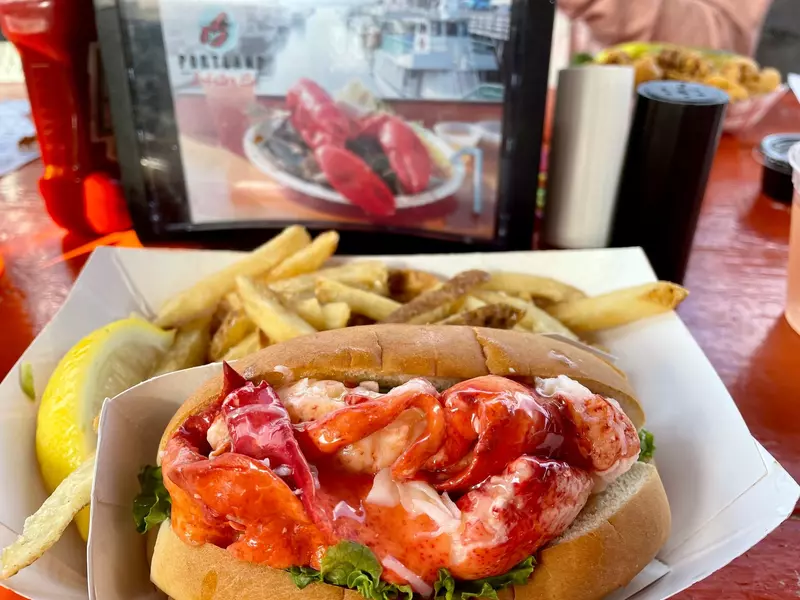 A lobster roll meal with the Portland Lobster Co. logo in the background