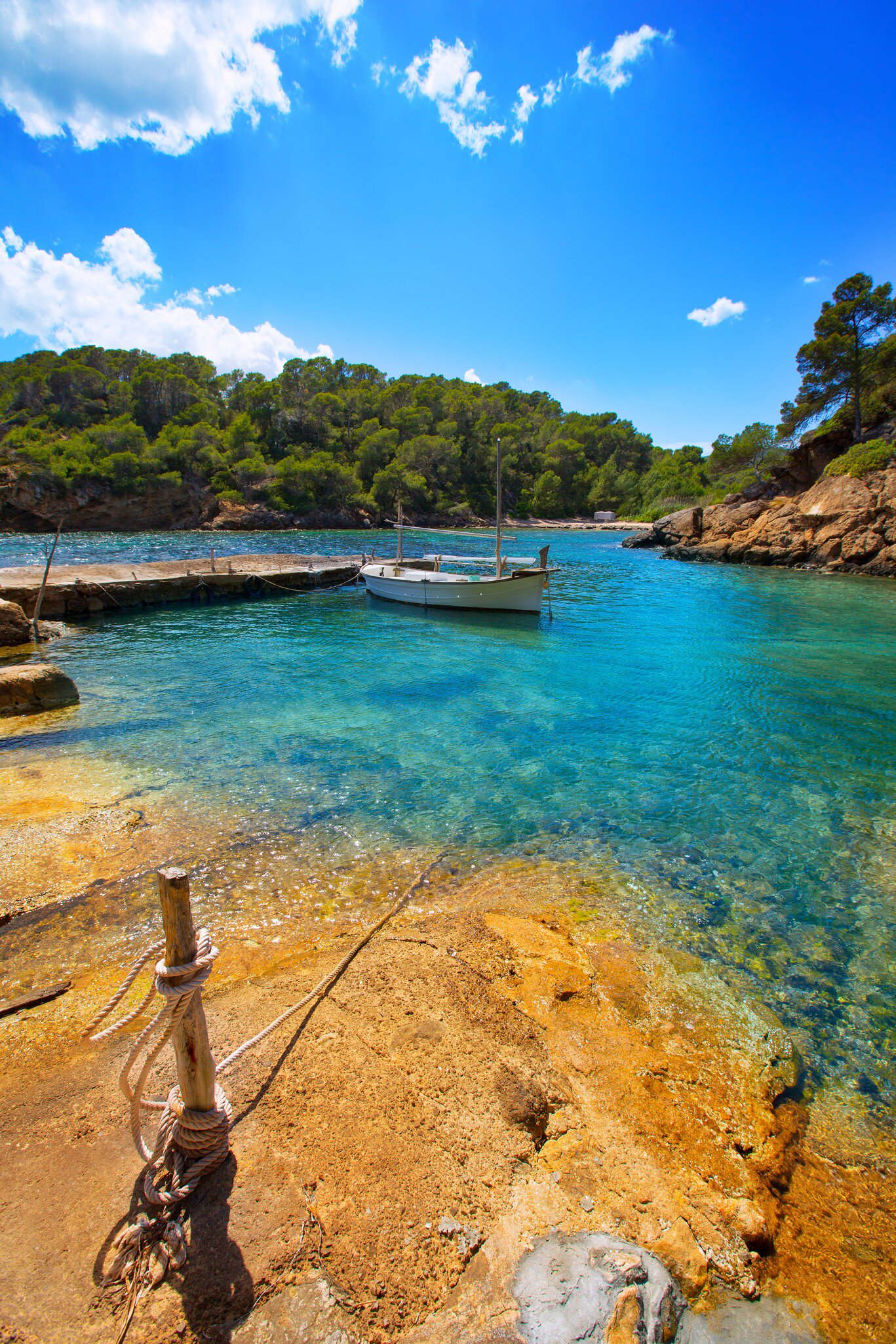 View of a boat in the water in Cala Mastella on the island of Ibiza in Spain.