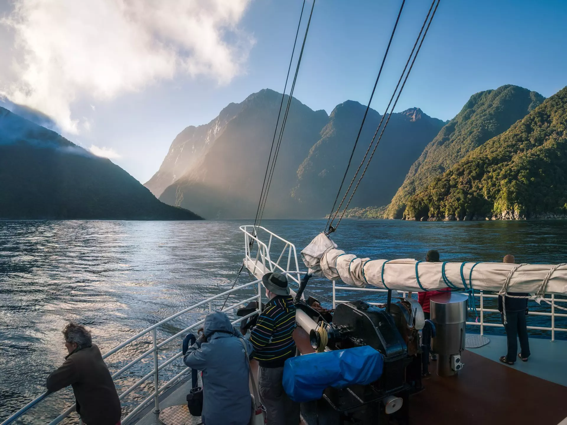 People standing on the bow of a boat during an early morning cruise in Milford Sound, Fiordland National Park, New Zealand.