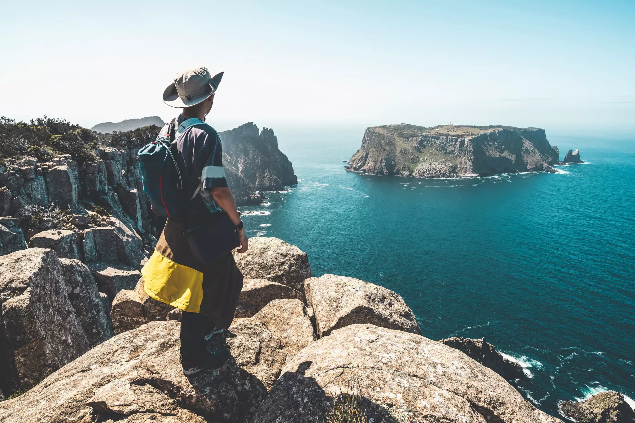 Young hiker on a rocky overlook on the beautiful coast cliff of Tasman National Park in Tasman peninsula, Three Capes Track near Port Arthur in Tasmania