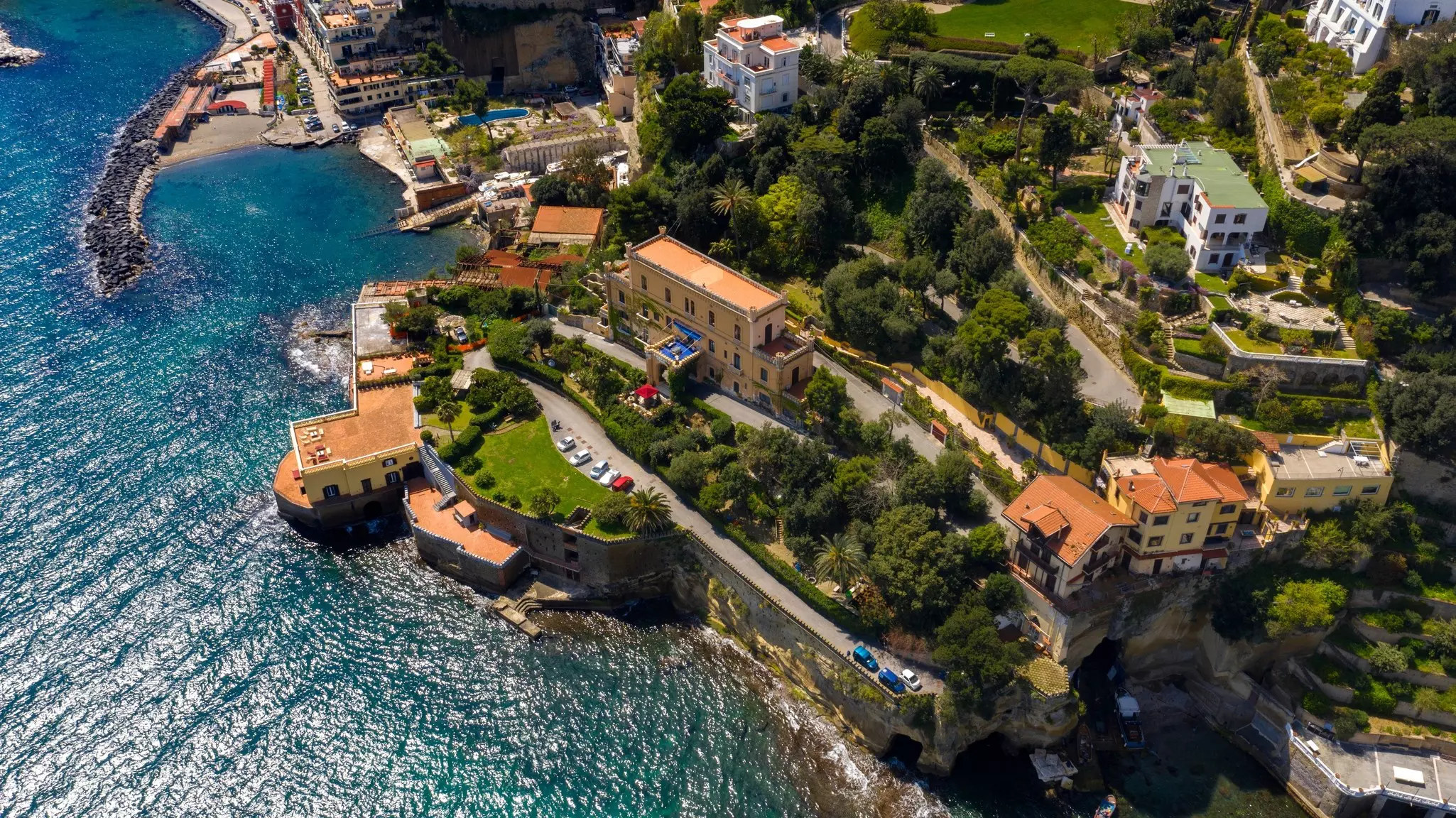 An aerial view of houses and windy roads on a cliff by the sea.