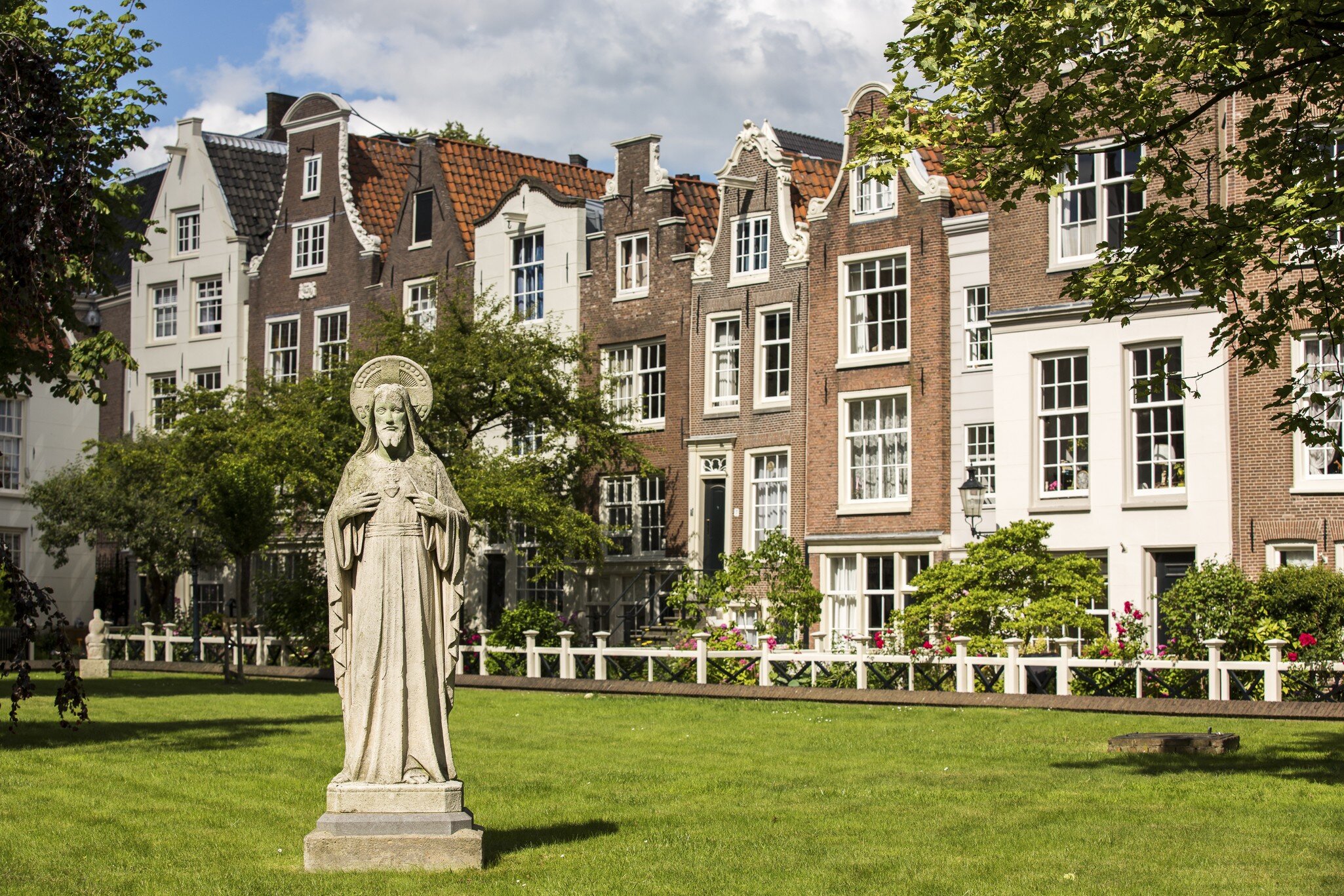 View of a statue on a lawn in Begijnhof, Amsterdam, on a sunny day.