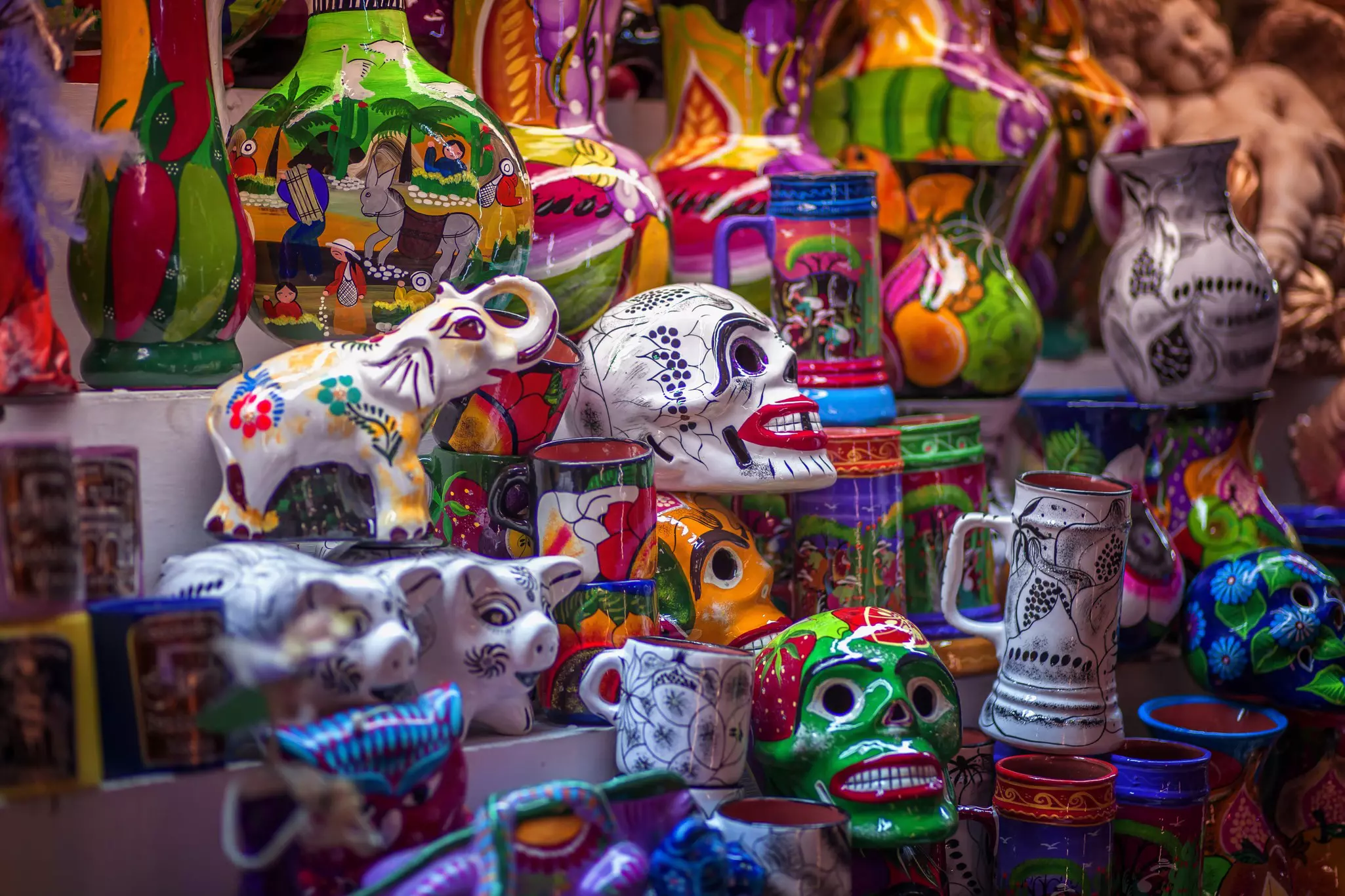 Colorful ceramic skulls, mugs, vases and other items clustered together at a market