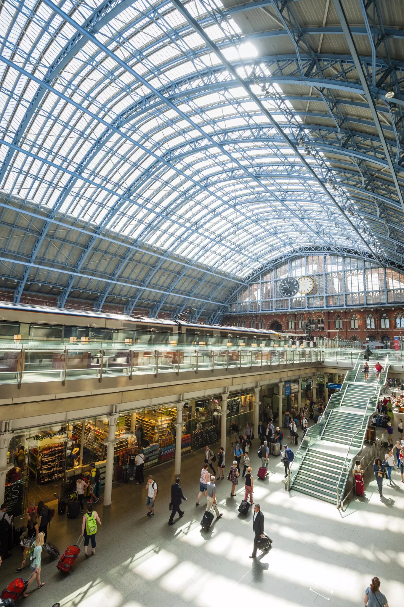 St Pancras train station, London. Sunlight shines through the roof as many people make their daily commute.