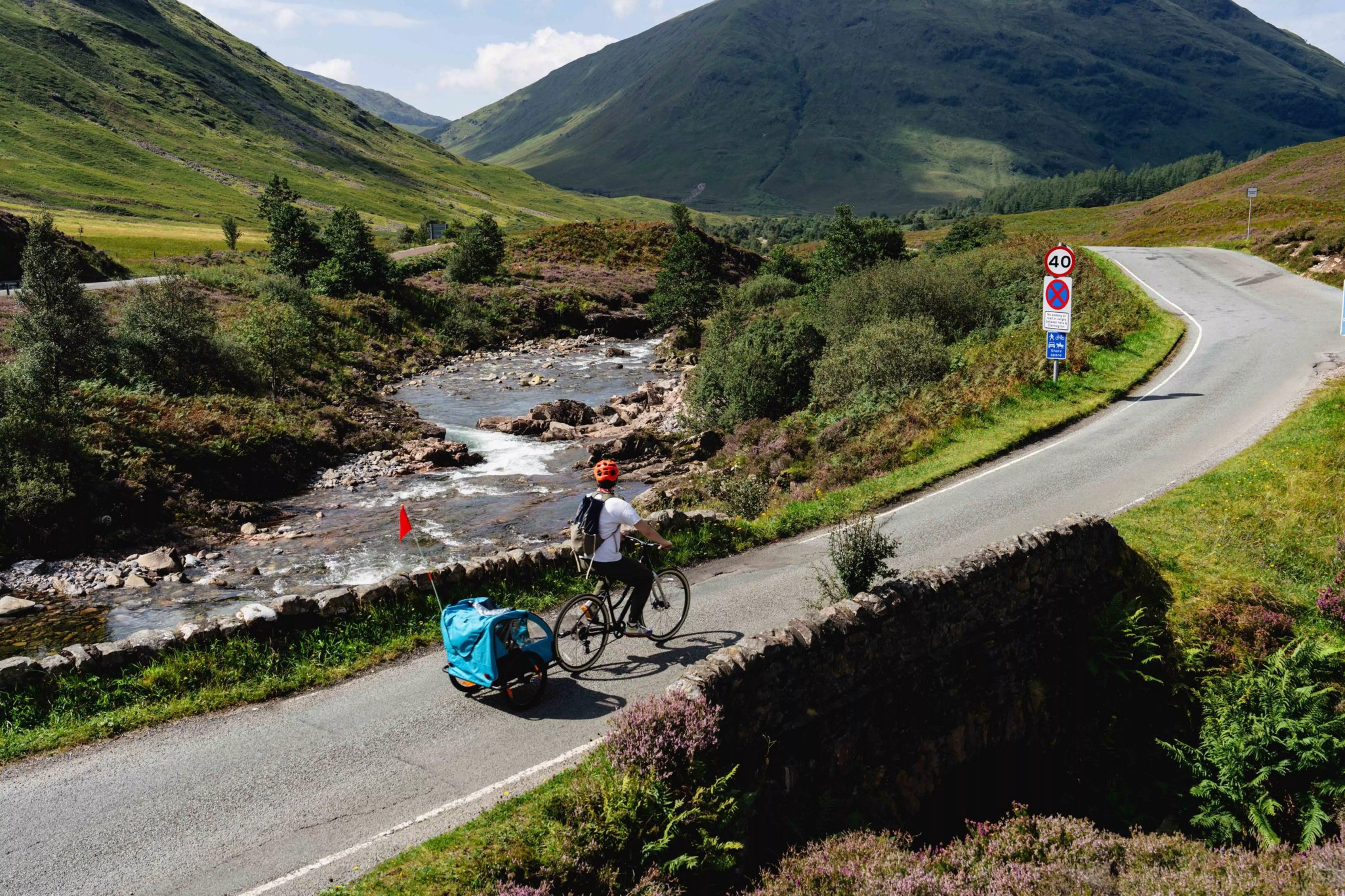 Charlie and family riding along a winding road beside a river in the Scottish Highlands.
