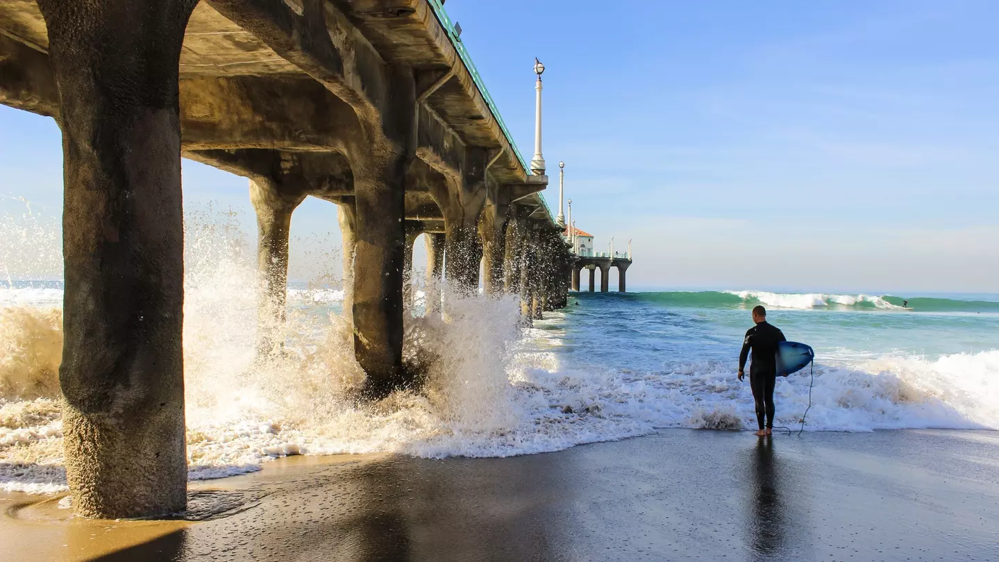 A surfer and his borad under Manhattan beach pier at Los Angeles California.