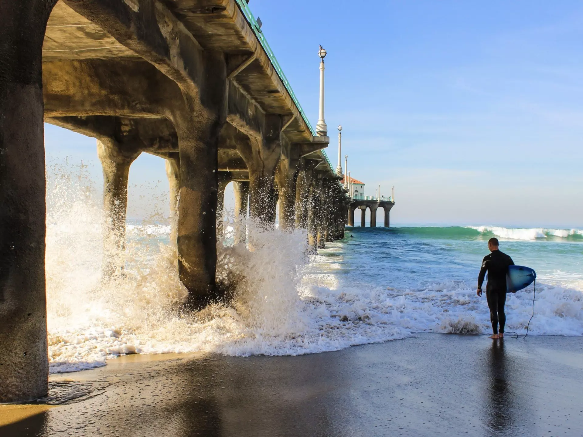 A surfer and his borad under Manhattan beach pier at Los Angeles California.
