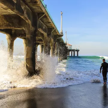 A surfer and his borad under Manhattan beach pier at Los Angeles California.