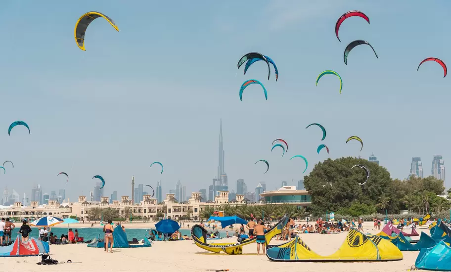 Colourful kites above a crowded Dubai beach, Burj Khalifa and city skyline behind, United Arab Emirates