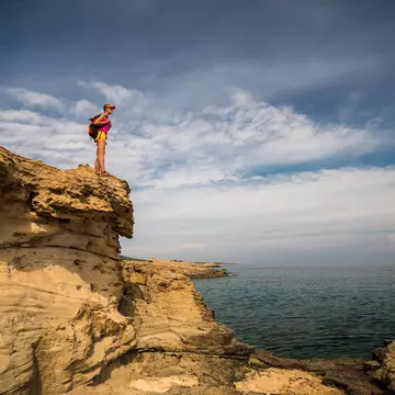 A women hiker on a rocky shoreline in the Akamas Peninsula, Cyprus
