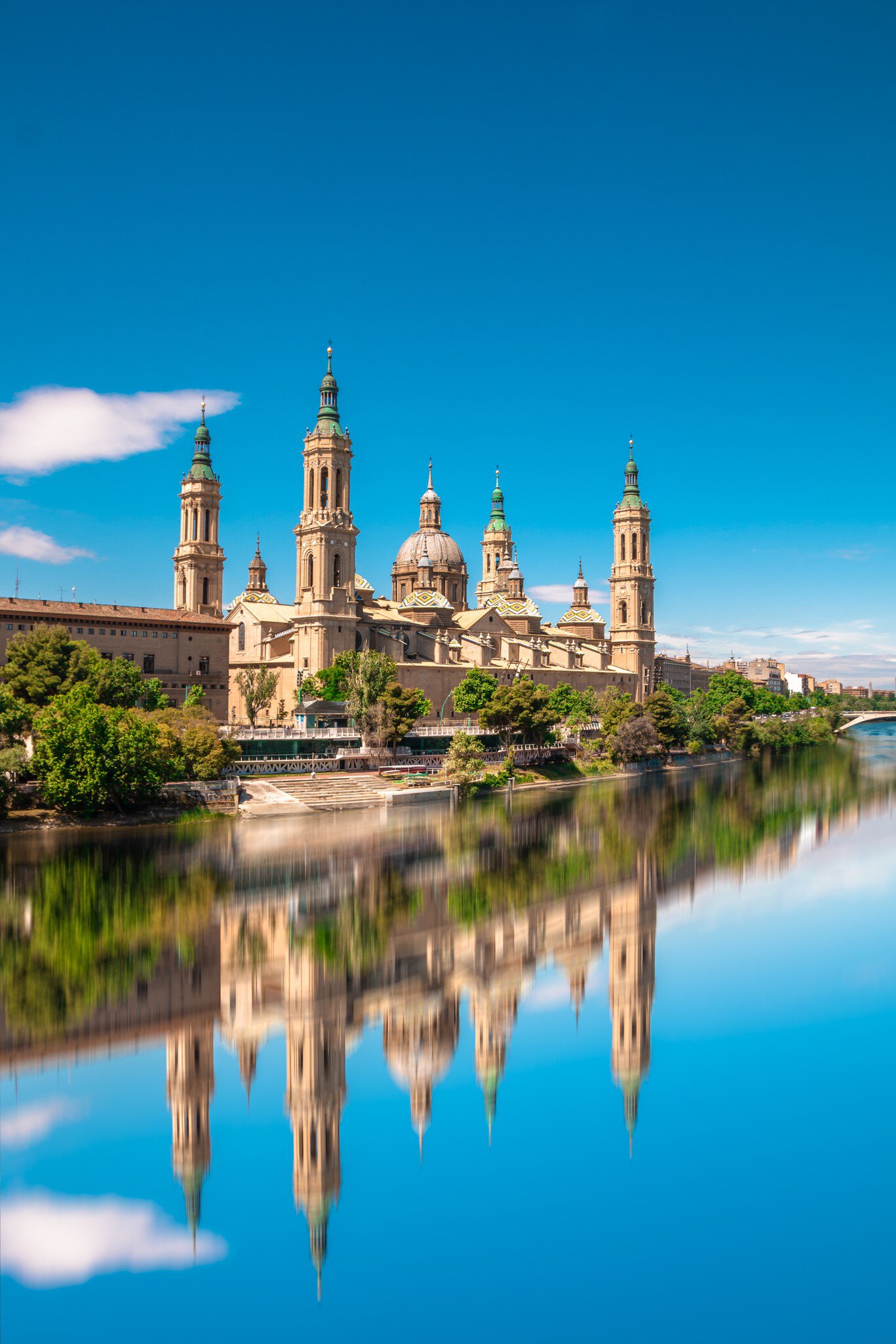View of the Basílica de Nuestra Señora del Pilar by the Ebro River on a sunny day in Zaragoza, Spain.