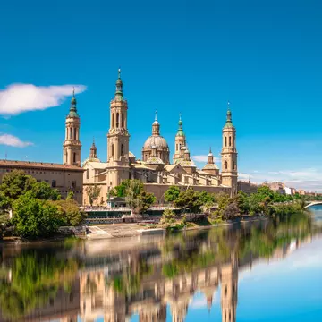 View of the Basílica de Nuestra Señora del Pilar by the Ebro River on a sunny day in Zaragoza, Spain.