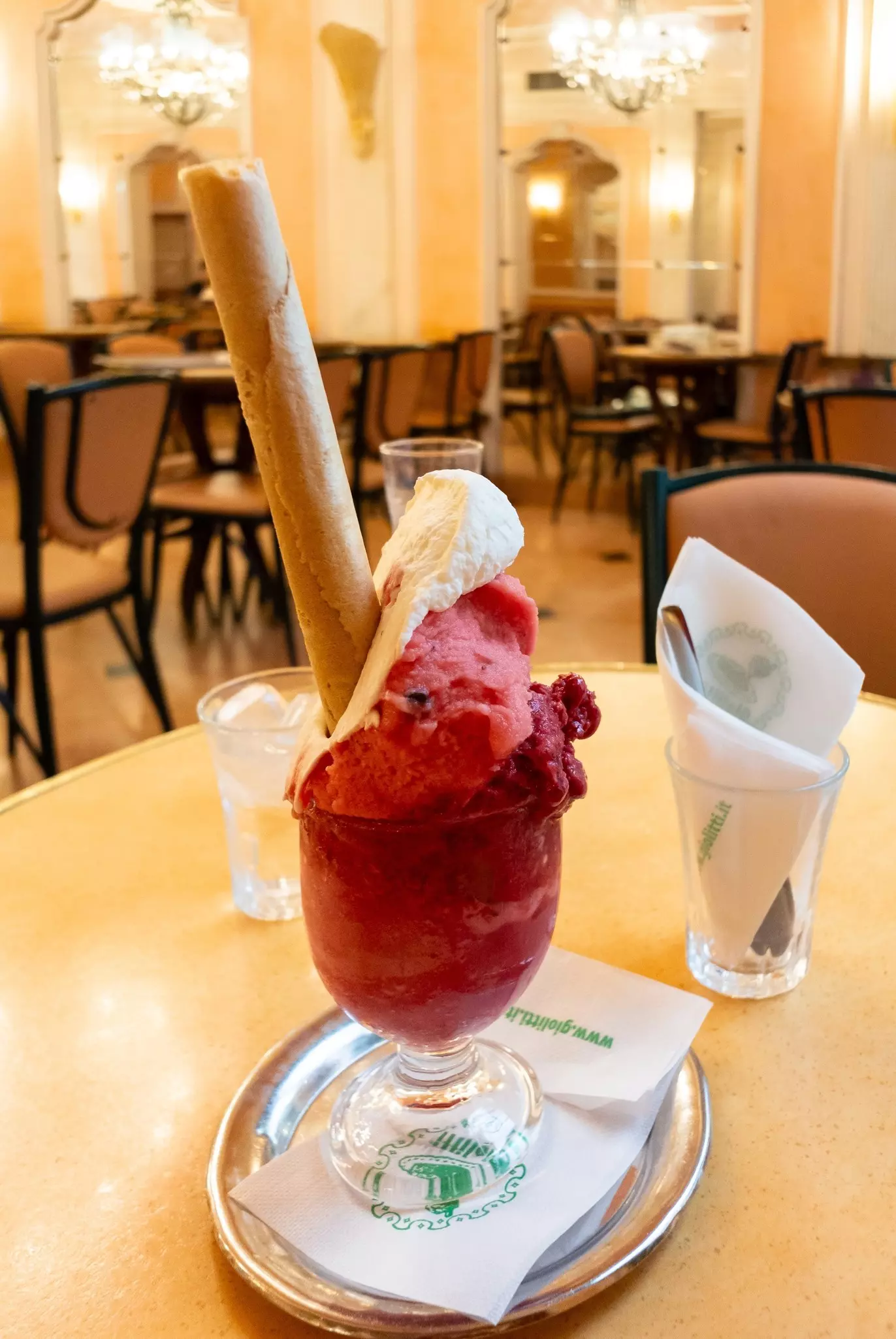 A cup of Gelato on the table with classic interior of Giolitti, one of the oldest gelateria in Rome. ,