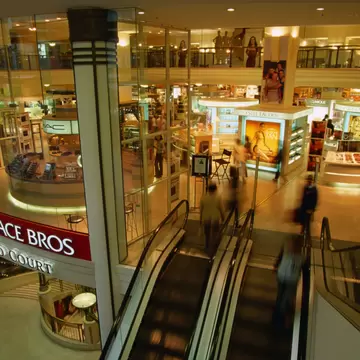 Overhead view of shoppers and an escalator inside Pitt St mall. Sydney, Australia.