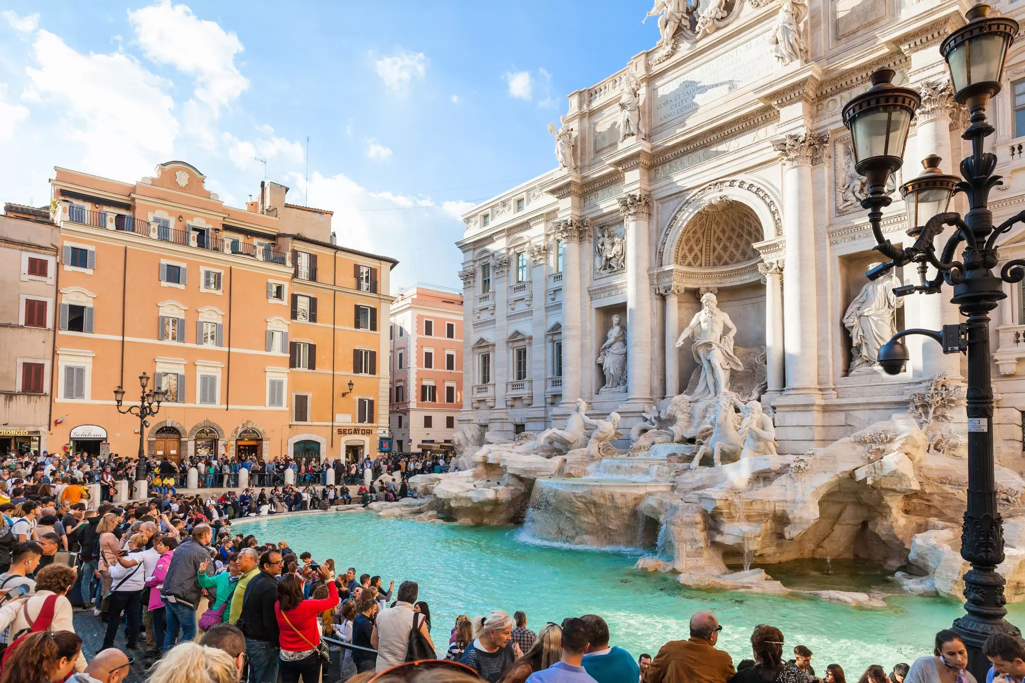 People gather at the pool in front of an ornate fountain in Rome