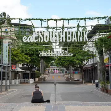  A single person sitting at the Stanley Street Plaza in South Bank Parklands. Brisbane, Australia.