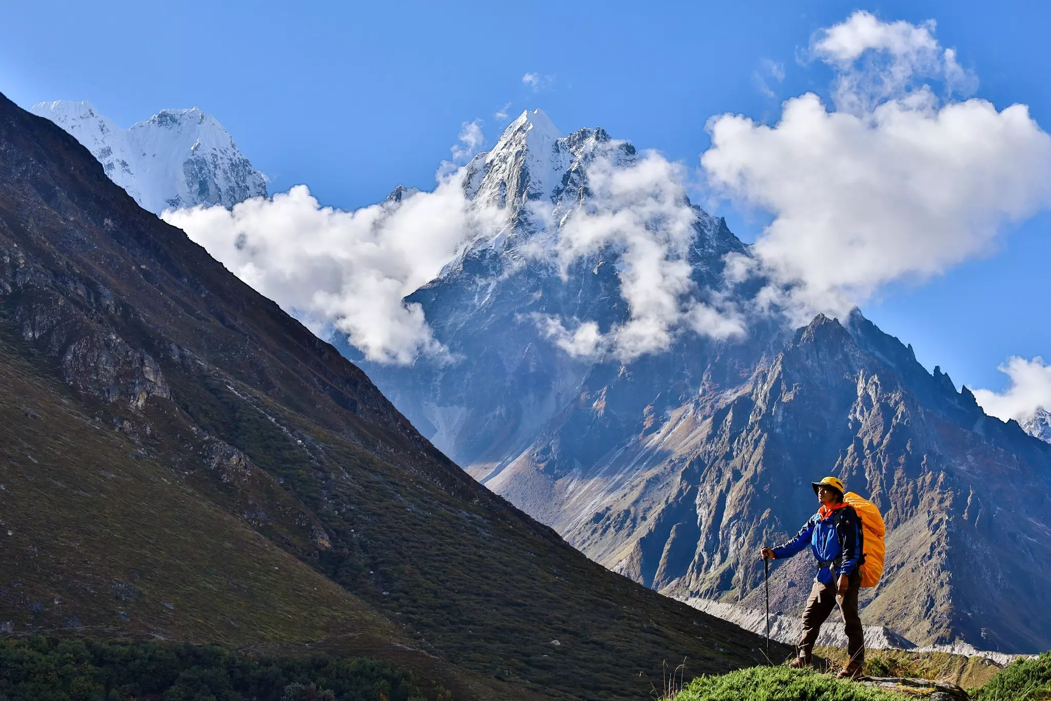 A lone trekker with a backpack stands in front of the stunning Kanchenjunga mountains at Kanchenjunga Base Camp in Nepal.