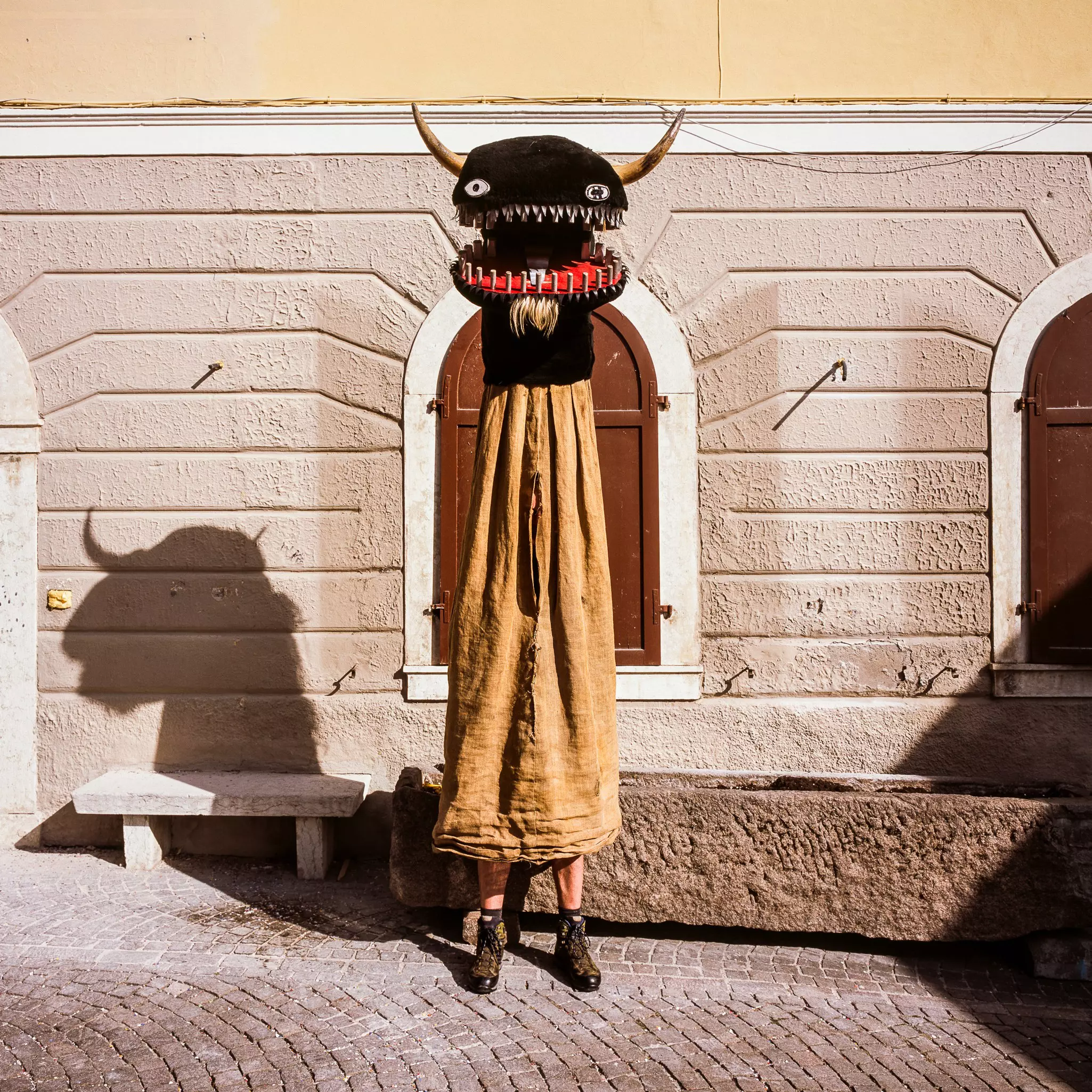 A person wears a costume with a black horned head.