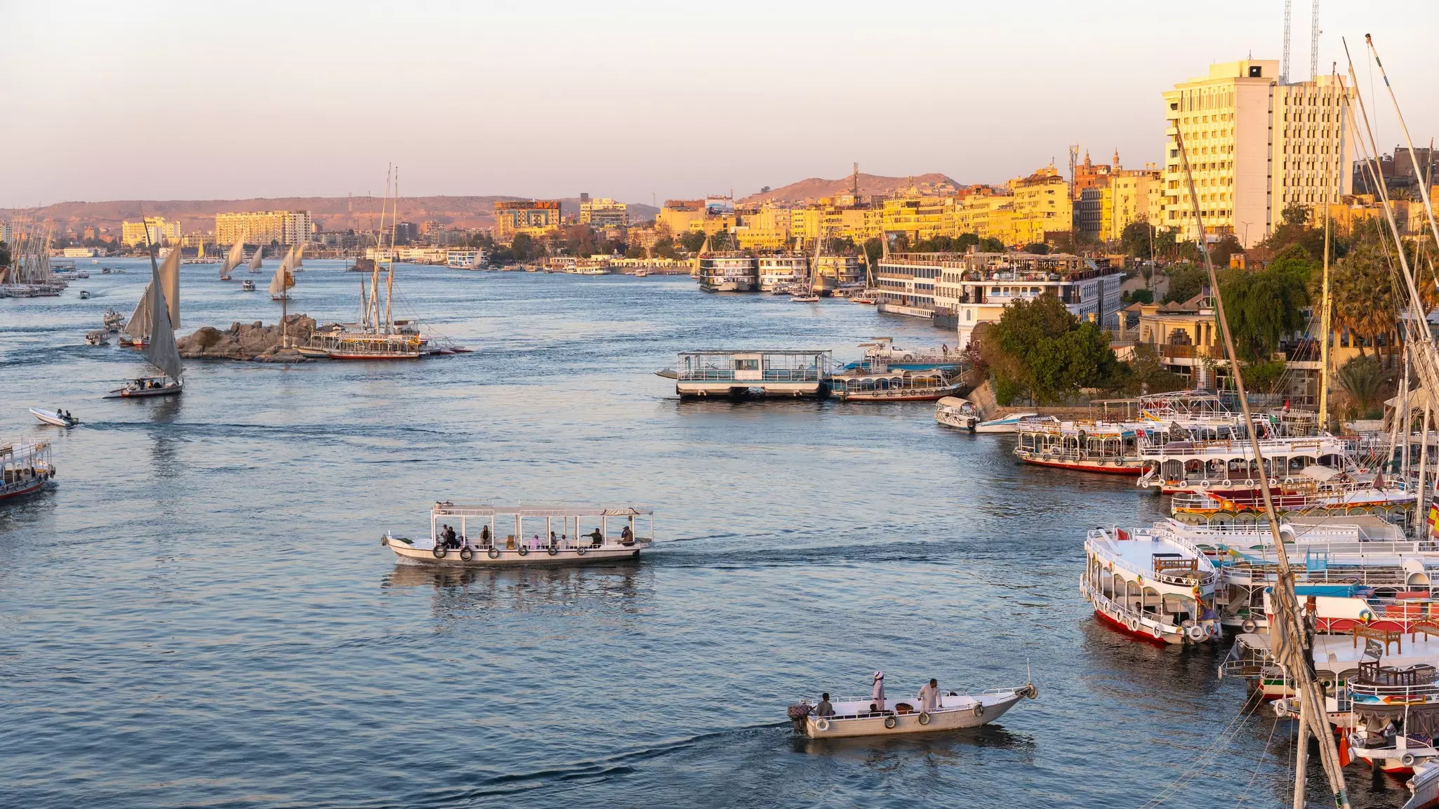 Boats navigating the nile river in aswan, with feluccas and a city skyline creating a scene of egyptian tradition and tourism, License Type: media, Download Time: 2026-03-15T18:47:59.000Z, User: bhealy950, Editorial: false, purchase_order: 65050 - Digital Destinations and Articles, job: Lonely Planet Online Editorial, client: Best things to do in Aswan, other: Brian Healy