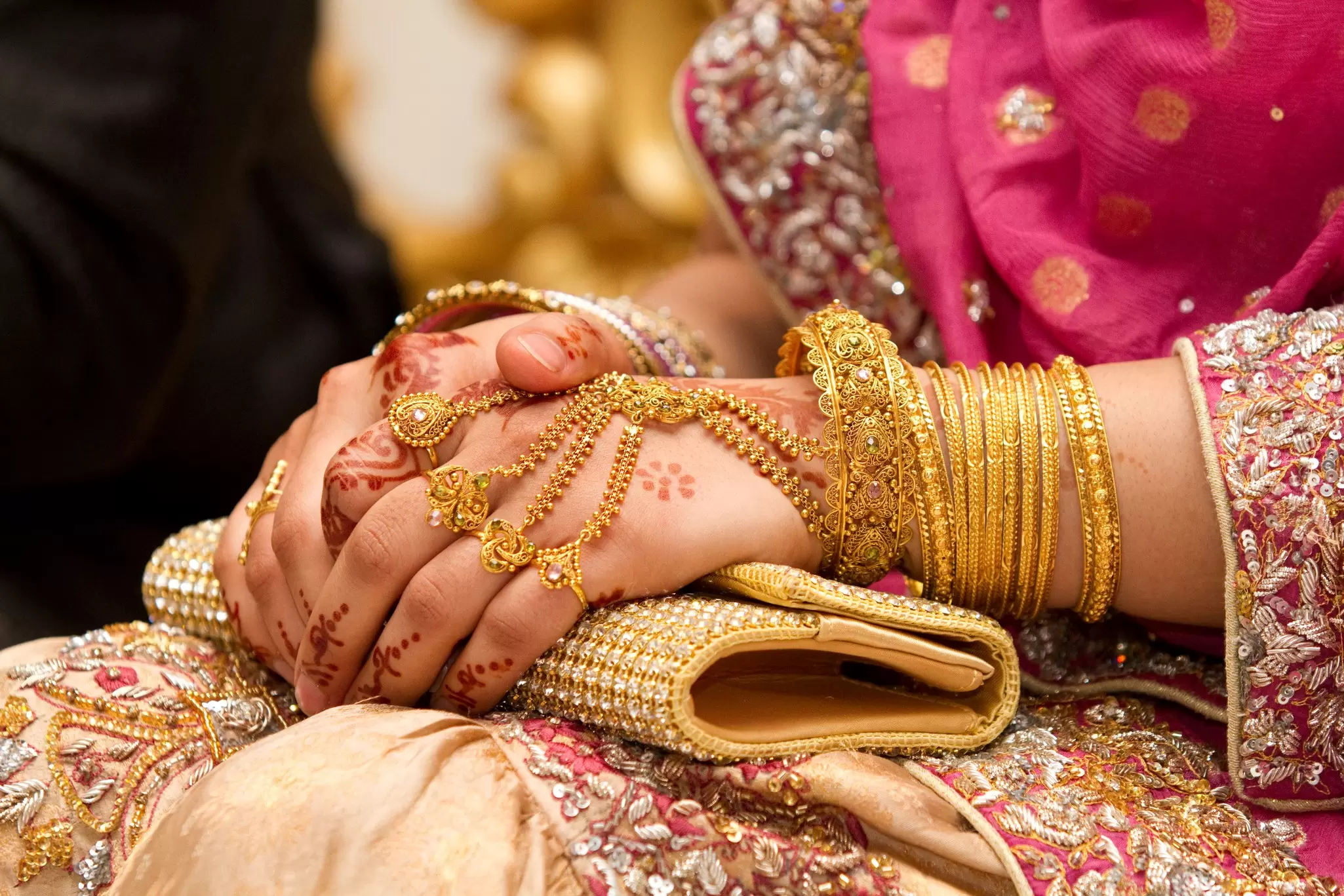 A bride's hands decorated with intricate henna and jewellery