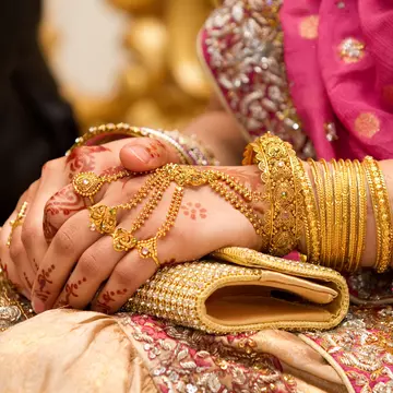Muslim brides hands decorated with henna and gold jewellery.
143999506