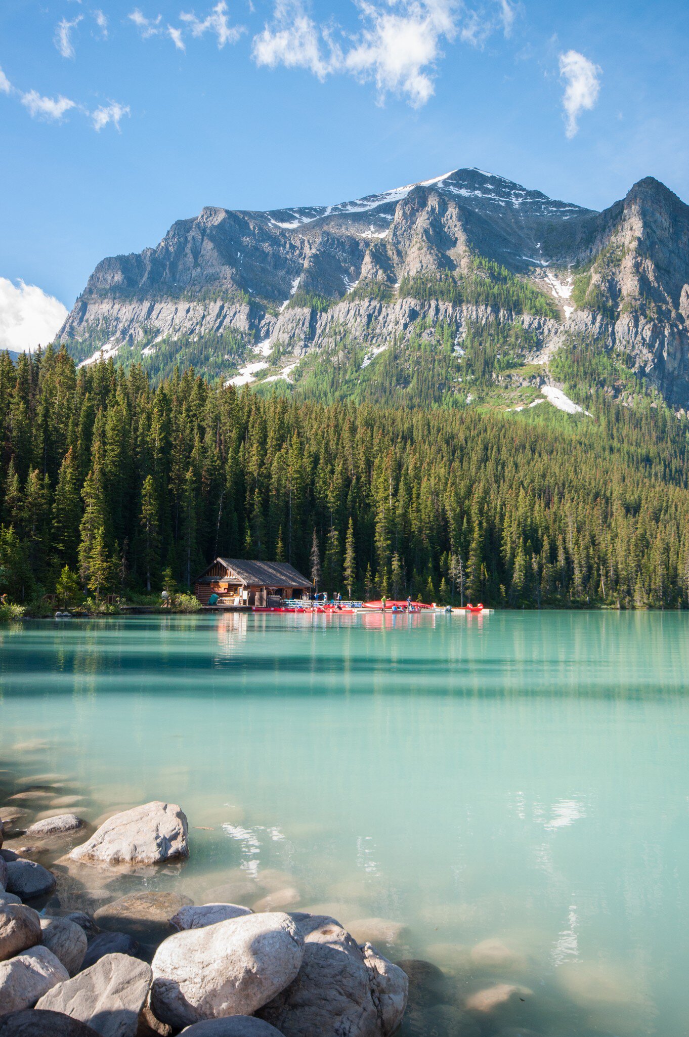 Turquoise lake surrounded by trees with snowy top mountain view in the background
