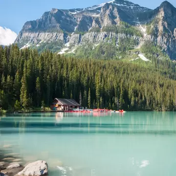 Turquoise lake surrounded by trees with snowy top mountain view in the background