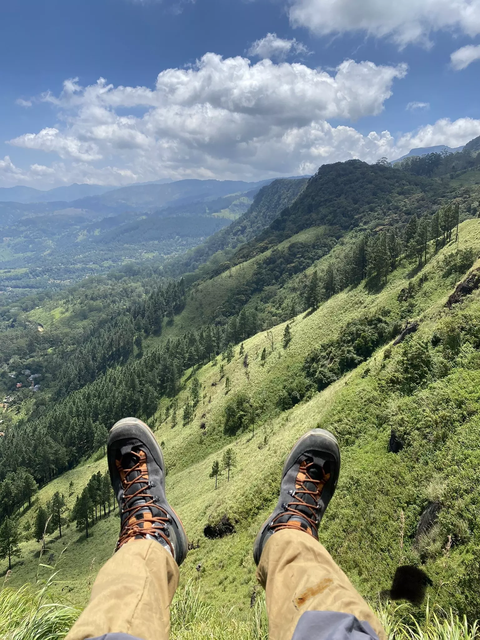 A hiker sits down to rest at a viewpoint with rolling hills stretching into the distance