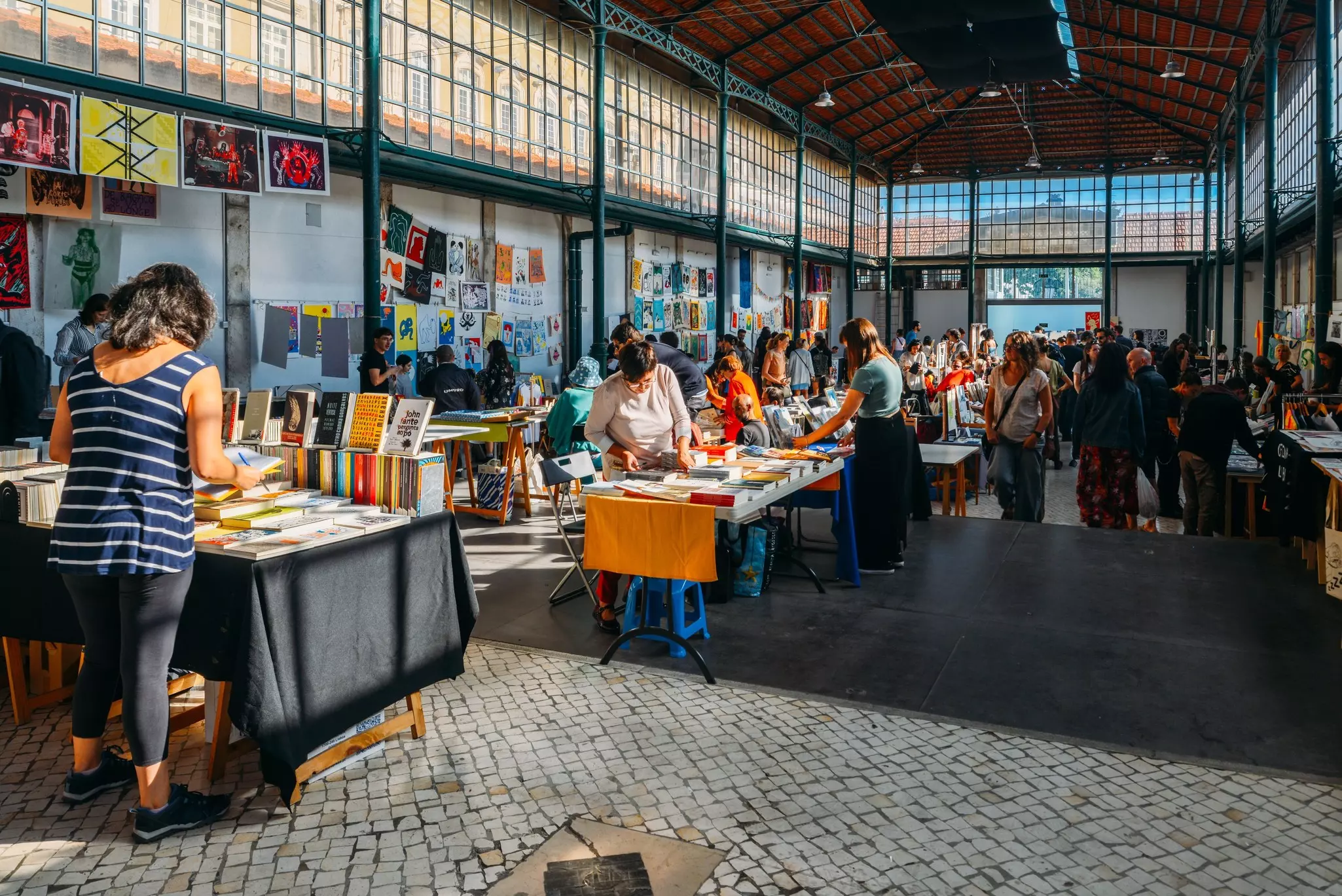 A covered market with people selling books and artwork.