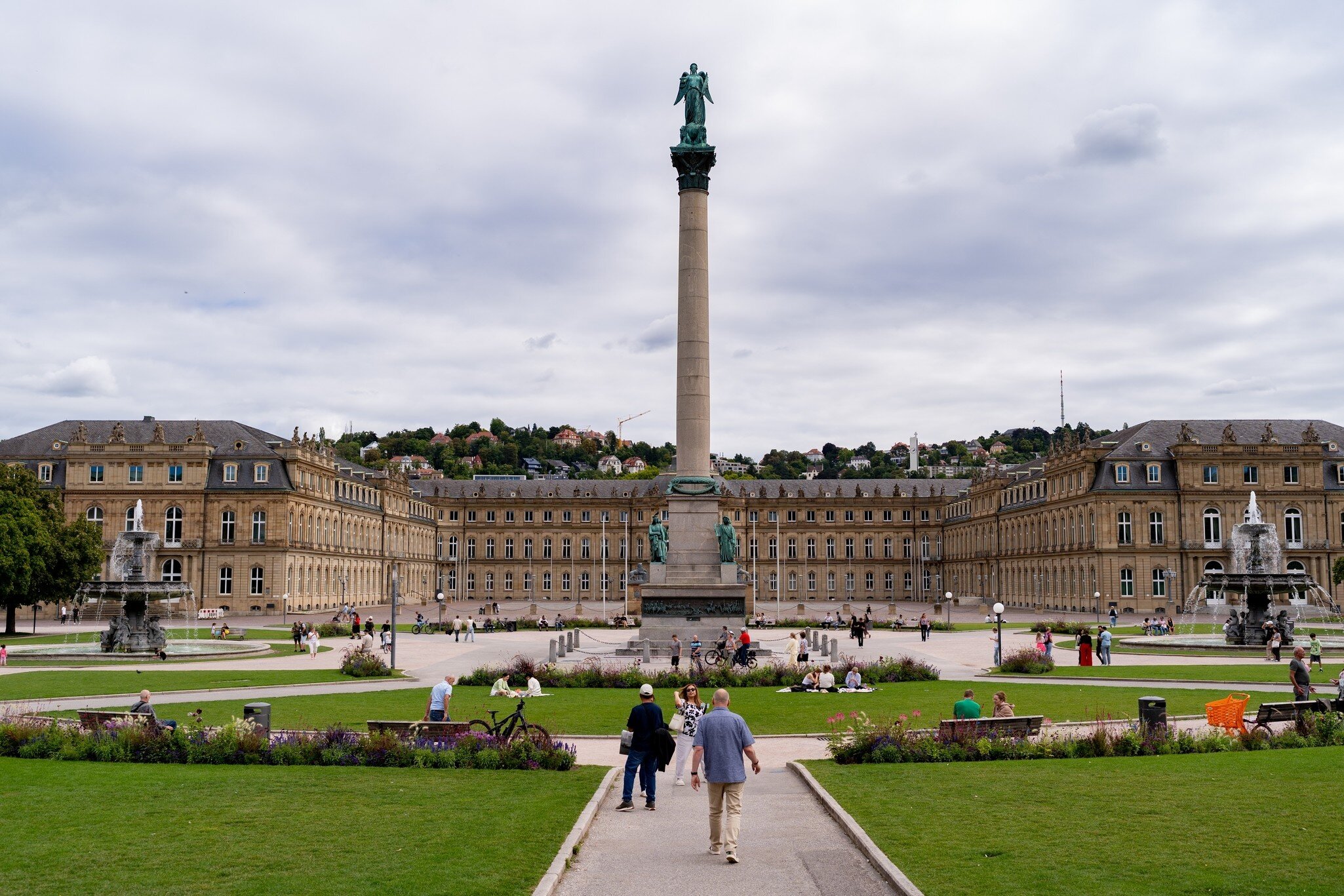 People walking towards the Neues Schloss with Jubilee Column at Schlossplatz in Stuttgart, Germany.