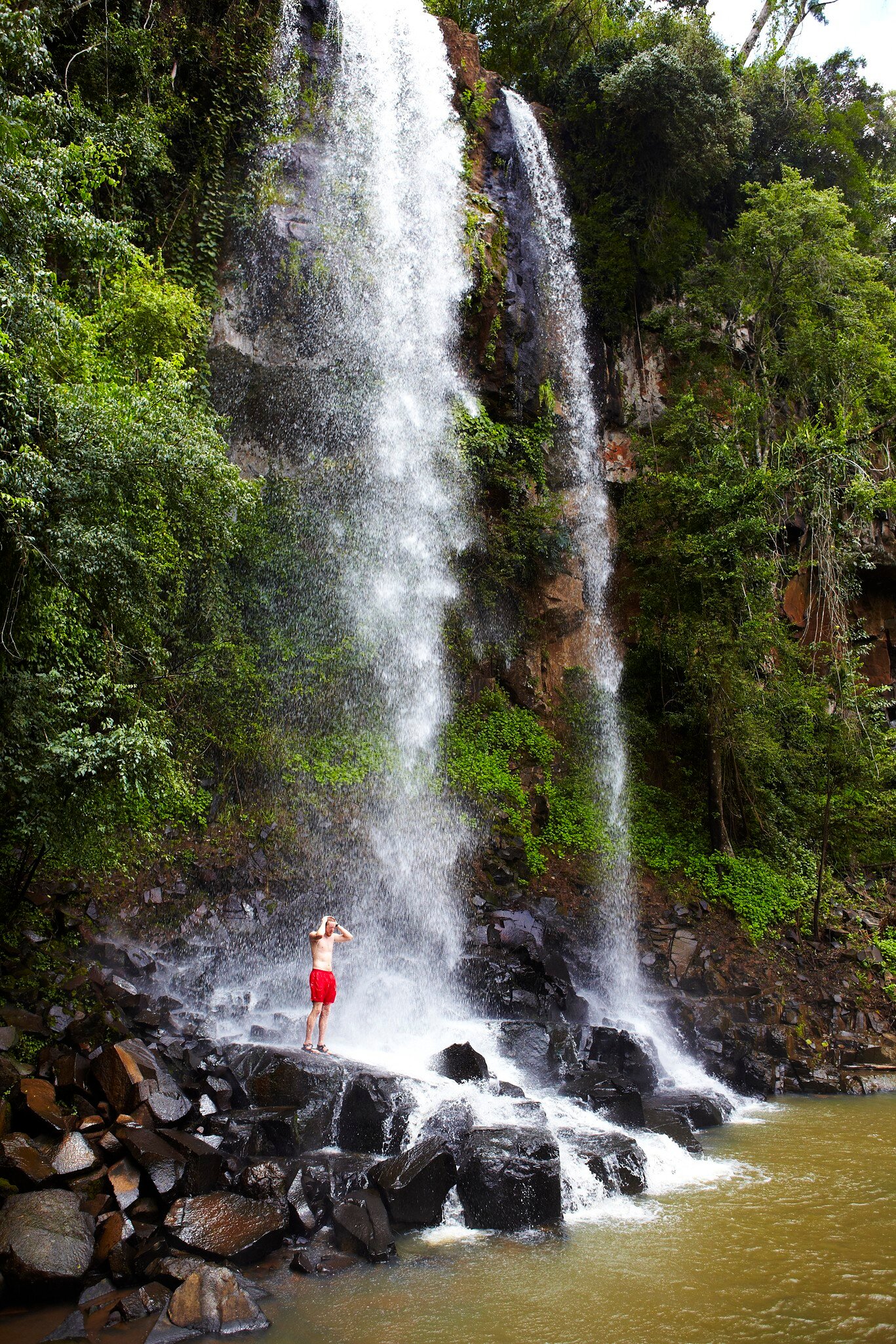 Man showering under Arrechea Falls in Parque Nacional Iguazú, Argentina.