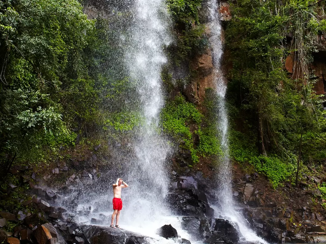 Man showering under Arrechea Falls in Parque Nacional Iguazú, Argentina.
