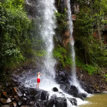 Man showering under Arrechea Falls in Parque Nacional Iguazú, Argentina.