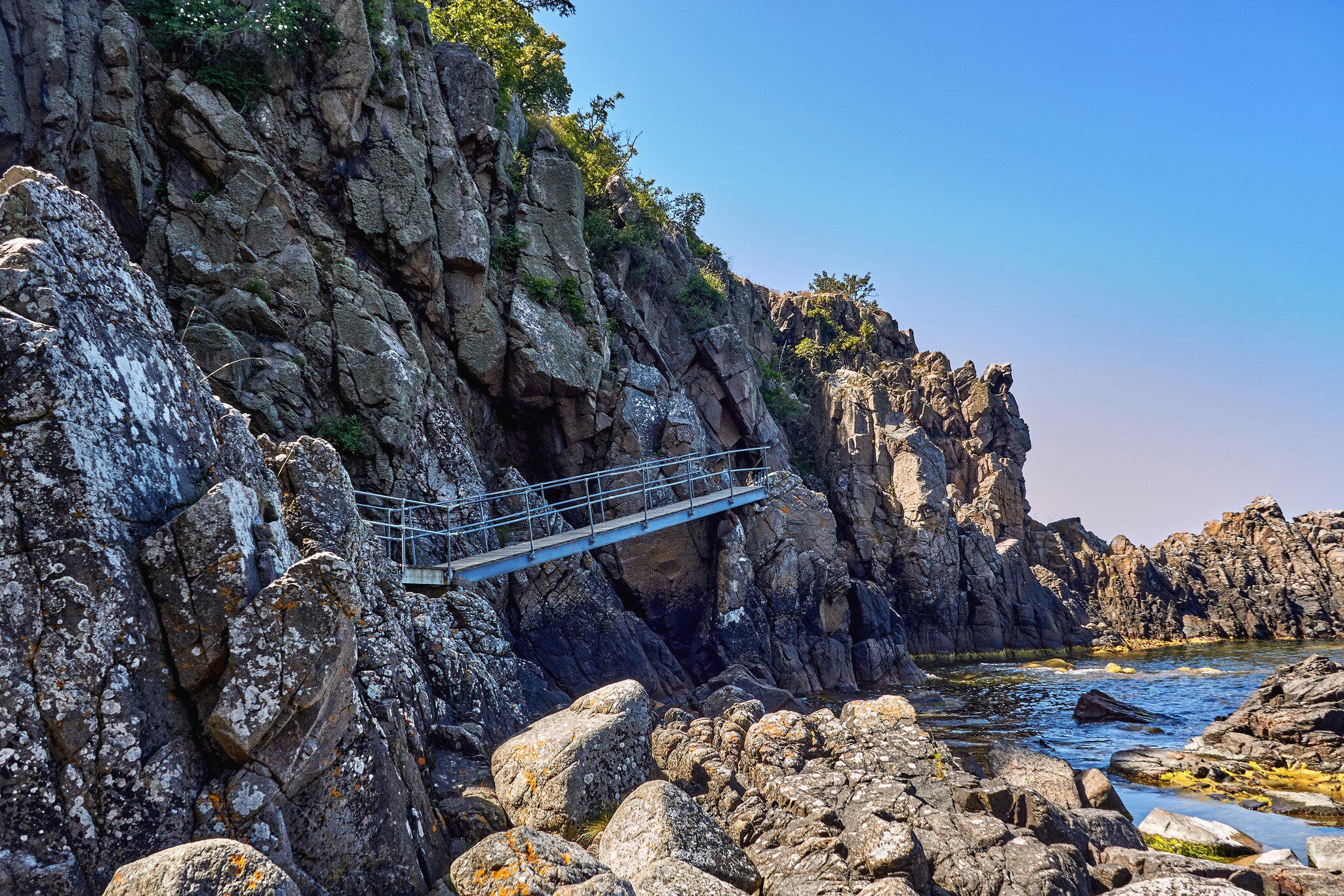 Footbridge leading to Sorte gryde (Black pot) sea cave located at the base of the cliff of Helligdomsklipperne (Sanctuary Cliffs) in the vicinity of Gudhjem Bornholm island, Denmark.