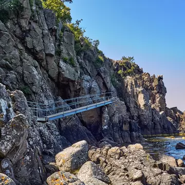 Footbridge leading to Sorte gryde (Black pot) sea cave located at the base of the cliff of Helligdomsklipperne (Sanctuary Cliffs) in the vicinity of Gudhjem Bornholm island, Denmark.