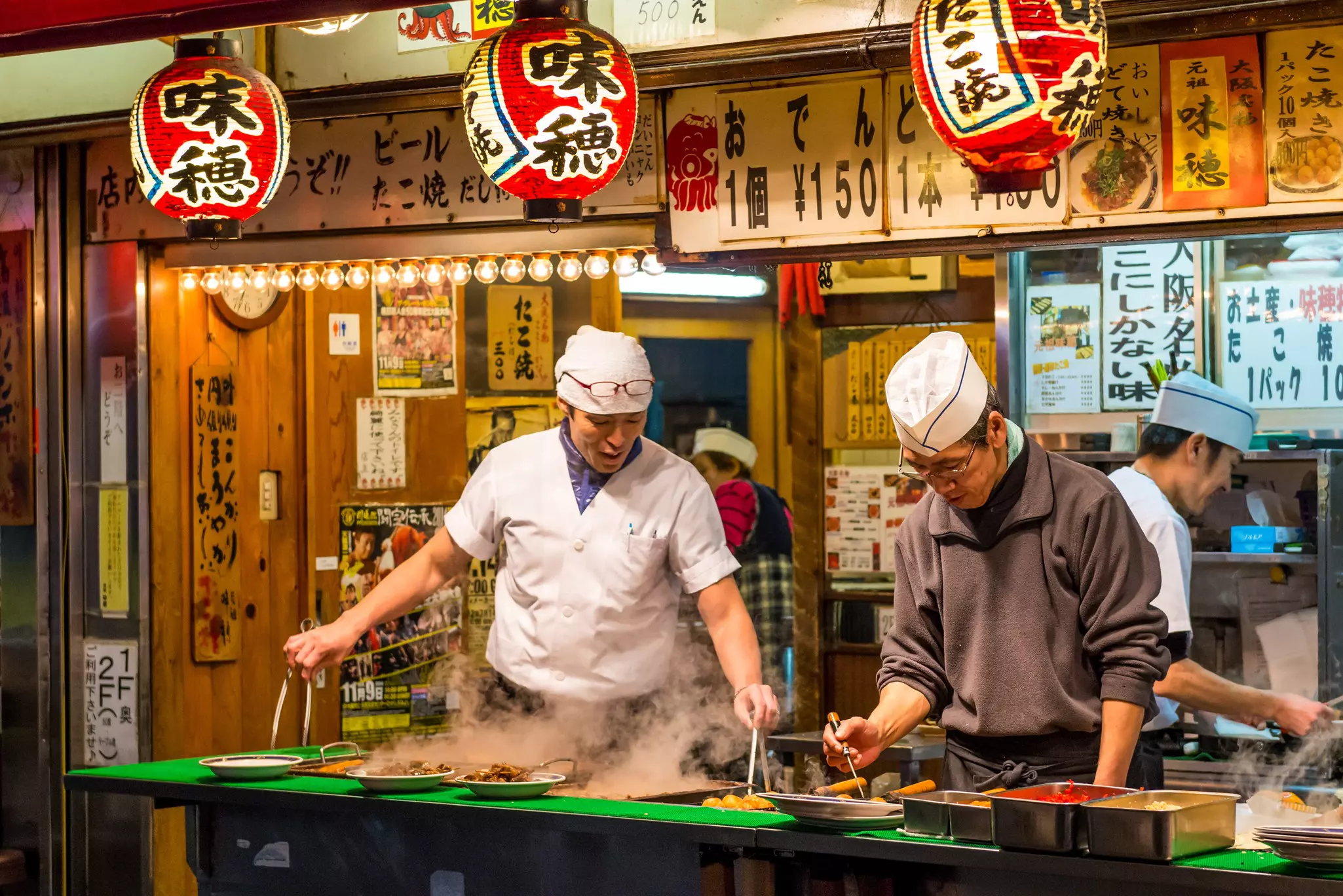 Two chefs cook at an open counter facing the street.