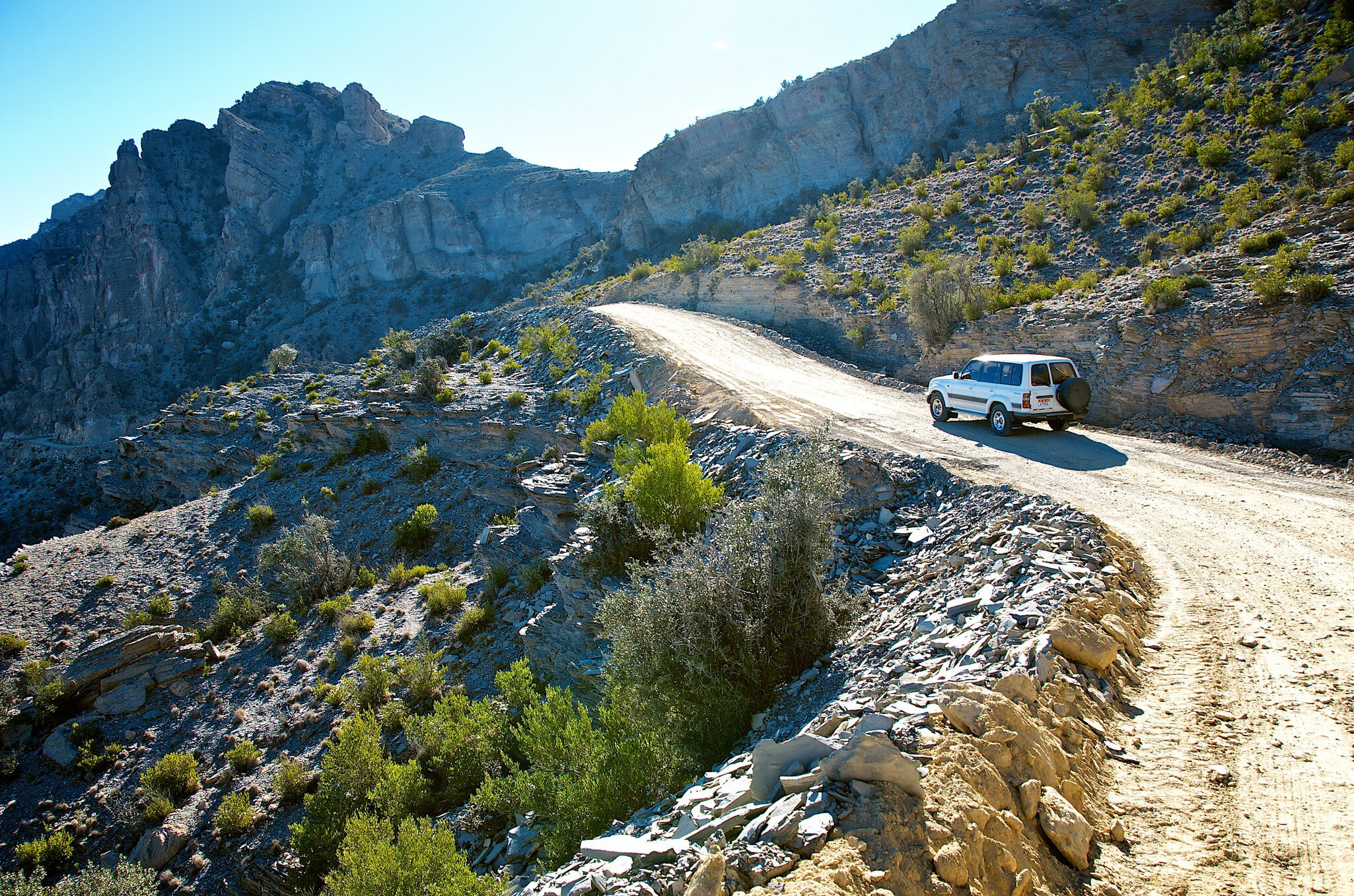 Car climbs dirt track in Wadi Bani Awf (Snake Gorge), Oman.