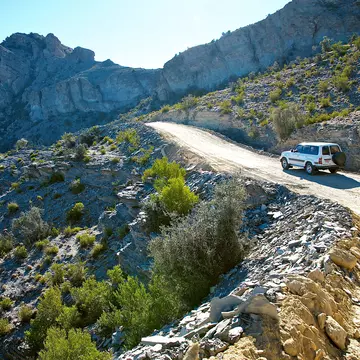 Car climbs dirt track in Wadi Bani Awf (Snake Gorge), Oman.