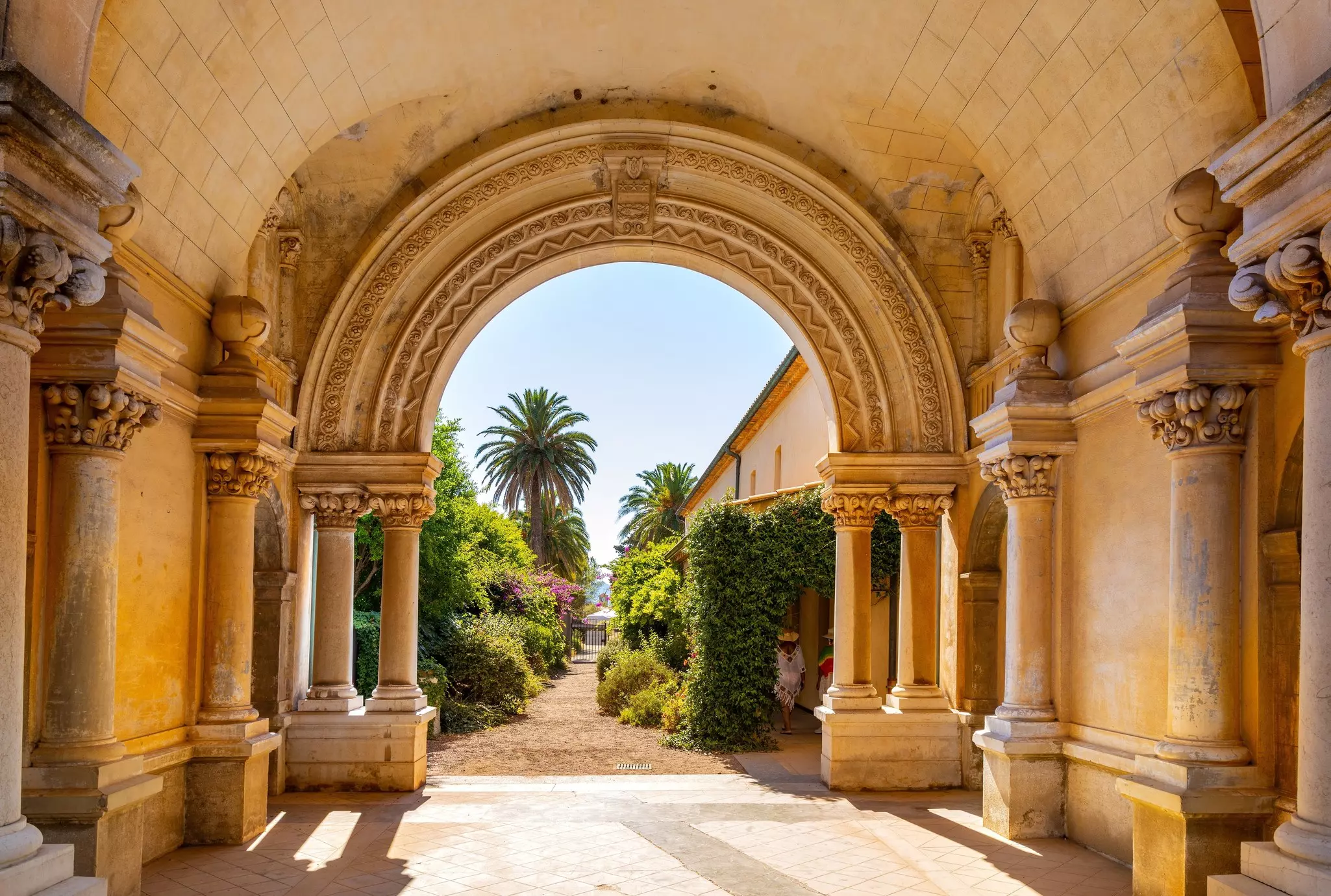 A pathway lined with greenery leading away from monastery cloisters
