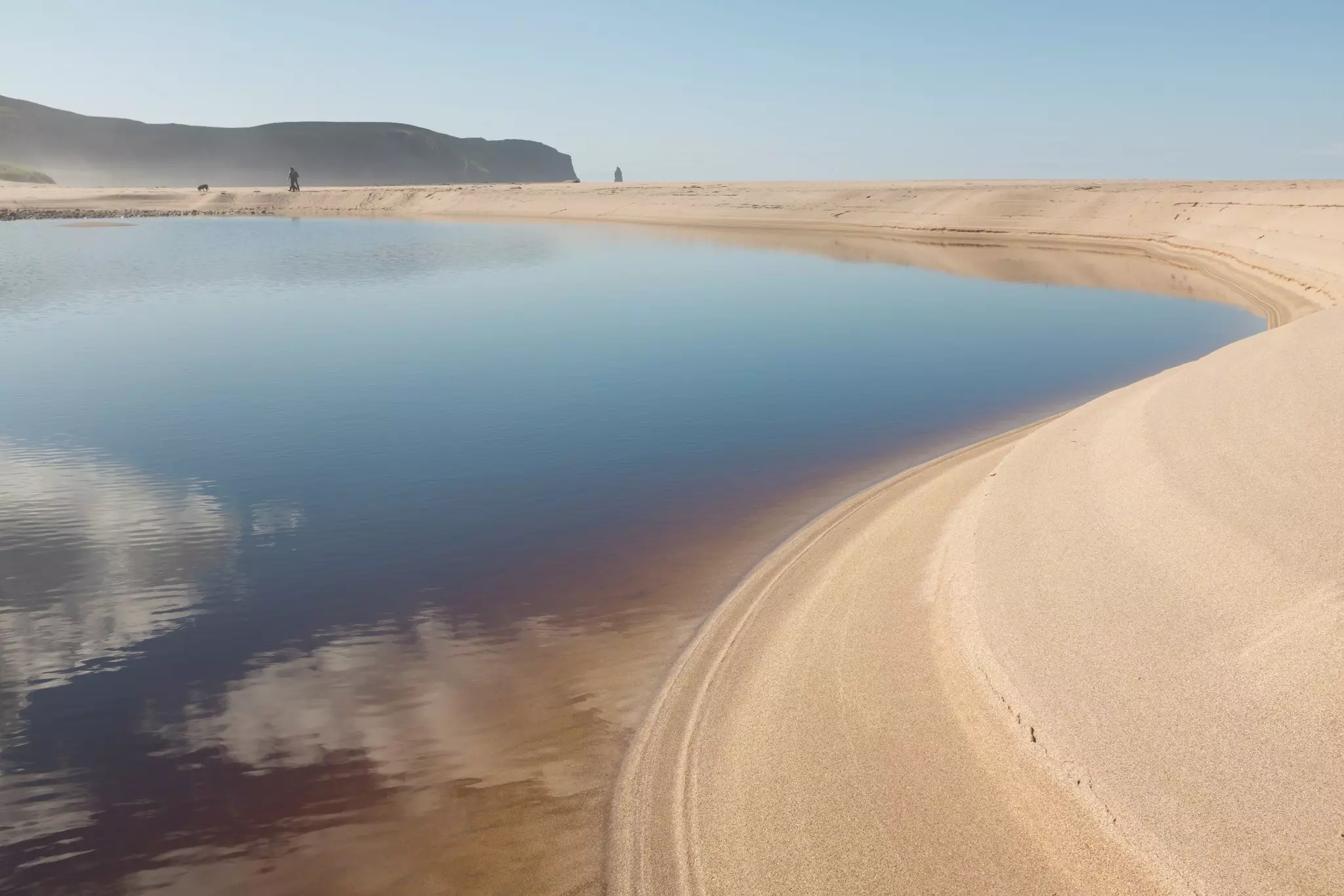 A huge sweep of red-gold sand on an empty beach that stretches far into the distance