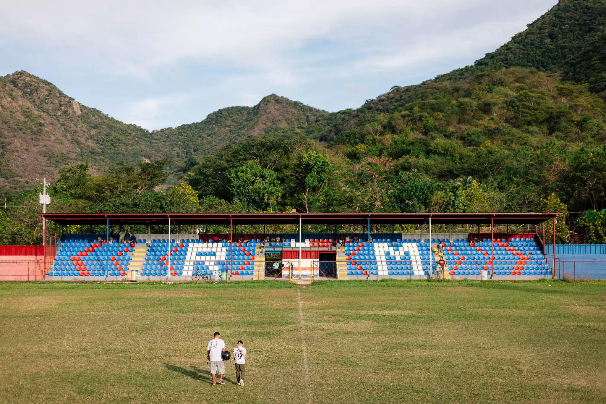 A scenic view of the Augusto Cesar Mendoza Arauz Stadium in Somoto, Nicaragua, with two fans on the pitch.