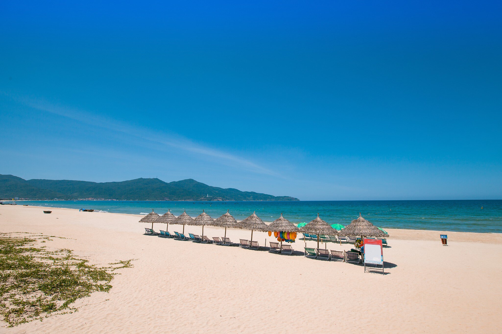 Beach umbrellas and deck chairs in front of My Khe beach in Da Nang, Vietnam.