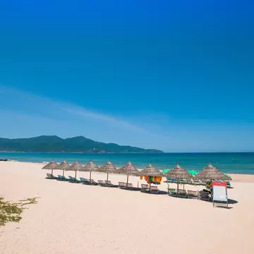 Beach umbrellas and deck chairs in front of My Khe beach in Da Nang, Vietnam.