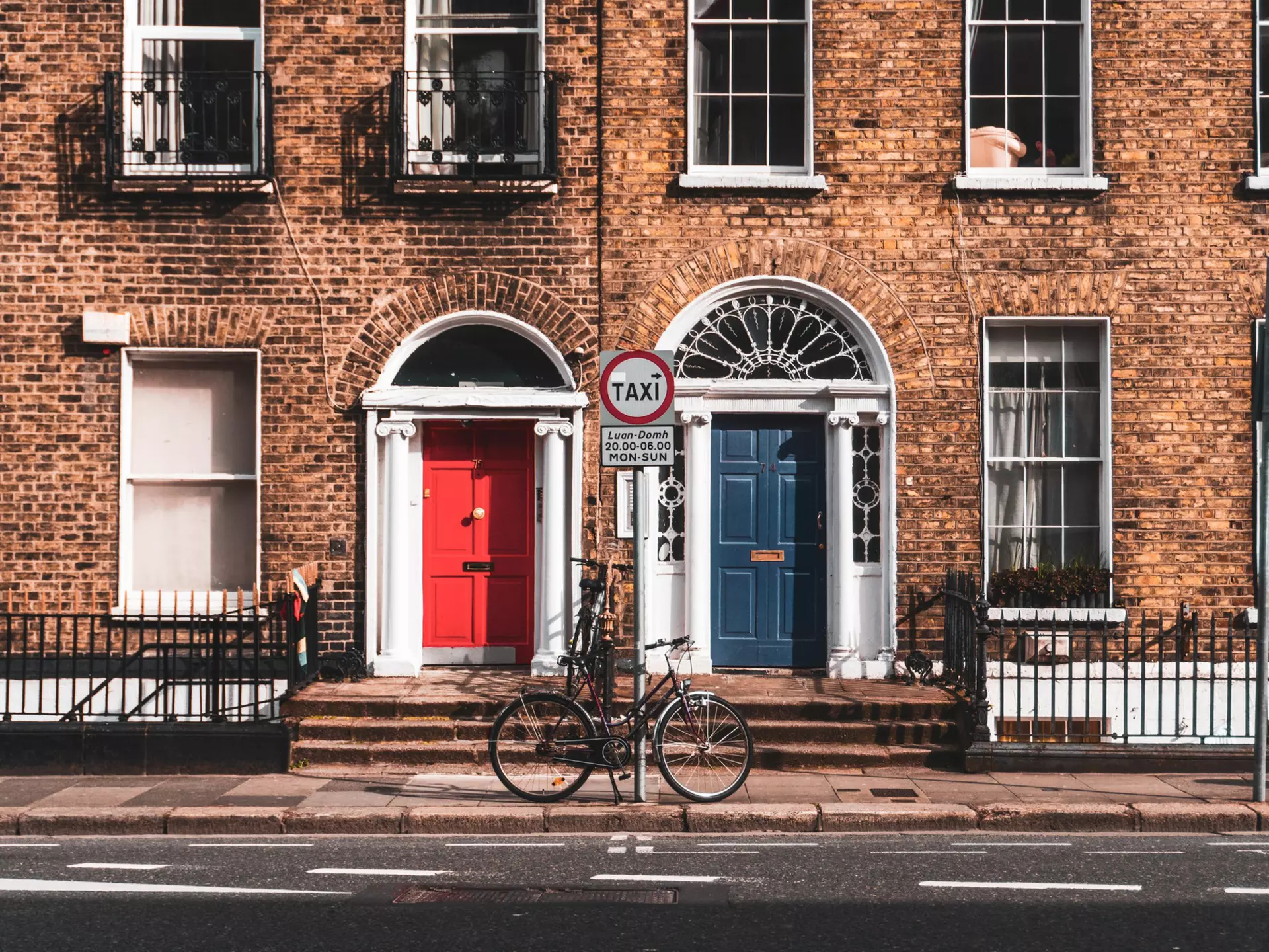 Brick buildings, with white trim; one has a red door, and the other has a blue door.
